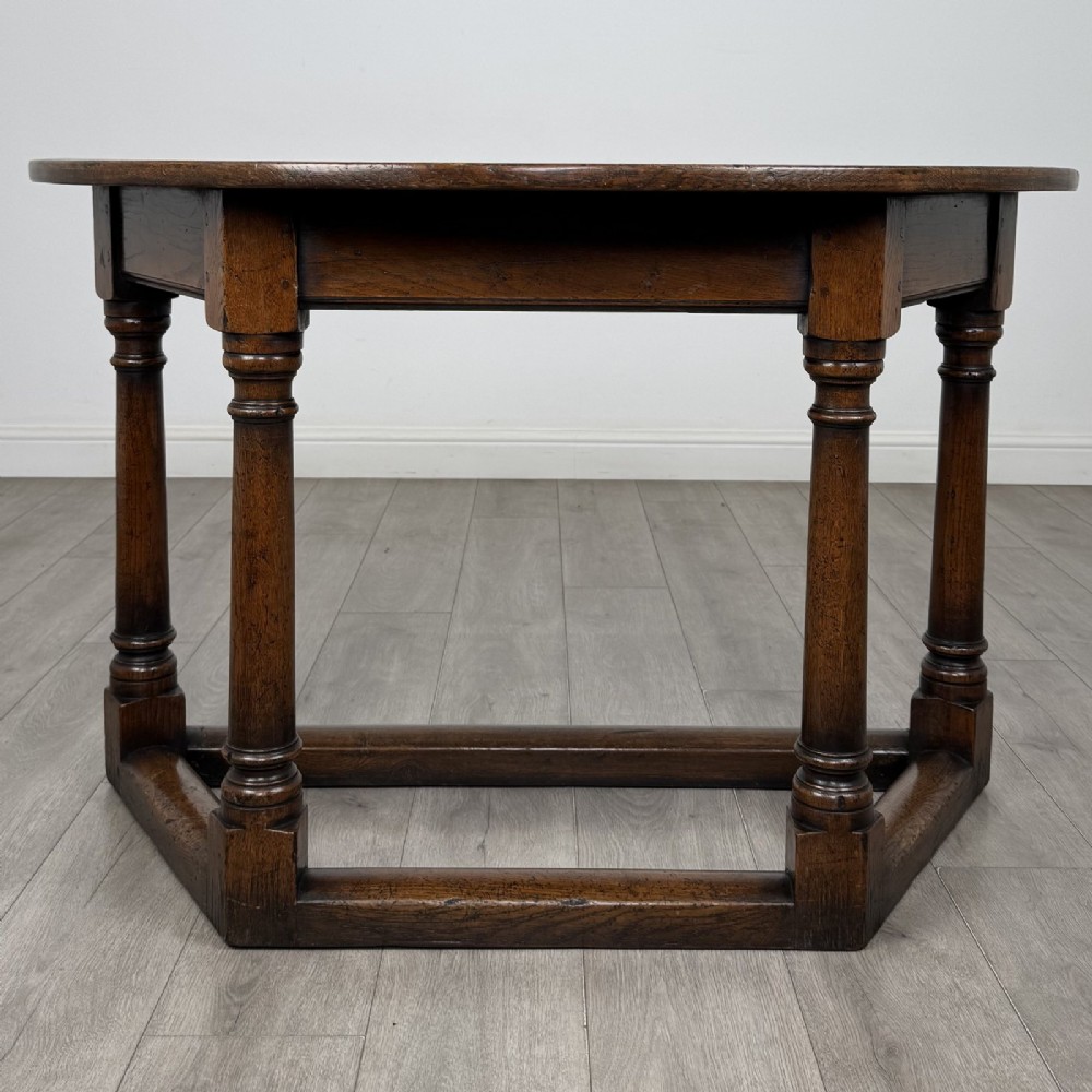 A dark oak demi-lune side table featuring turned legs and a low perimeter stretcher base.