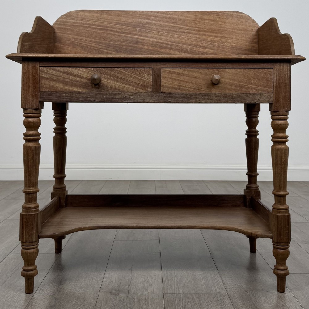 A Victorian mahogany washstand featuring a raised rear gallery, two frieze drawers with timber knobs, turned legs, and a lower shelf.