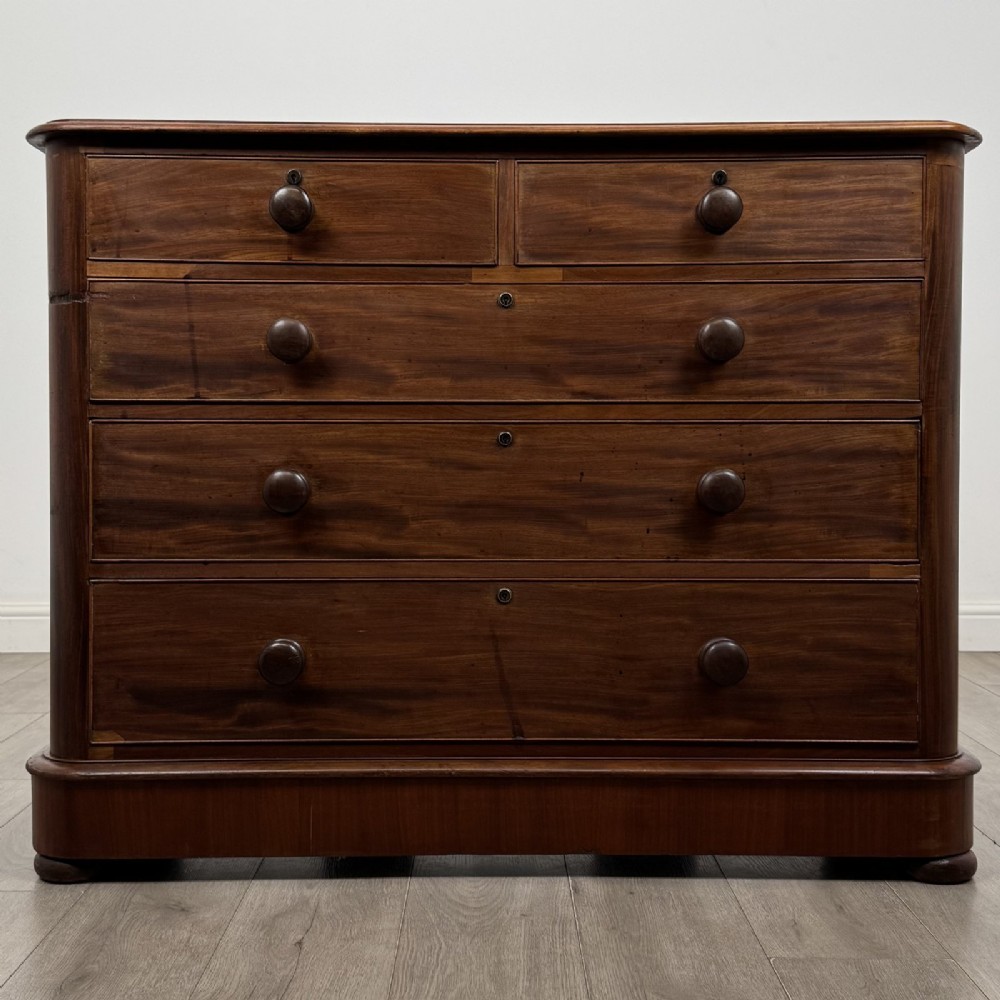 An antique Victorian mahogany chest of drawers featuring two short drawers above three long graduated drawers with turned knobs and bun feet.