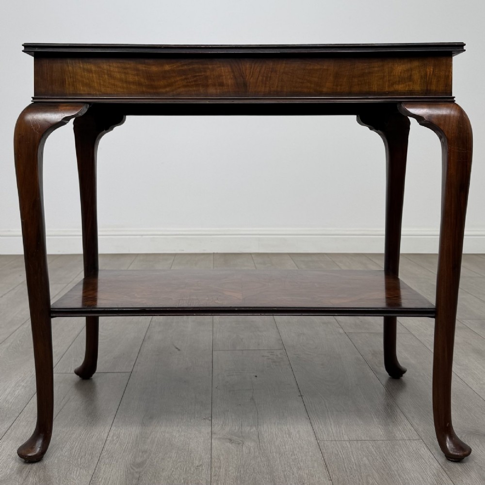 An Edwardian burr walnut side table featuring cabriole legs, pad feet, a lower shelf, and a rectangular top with deep apron.