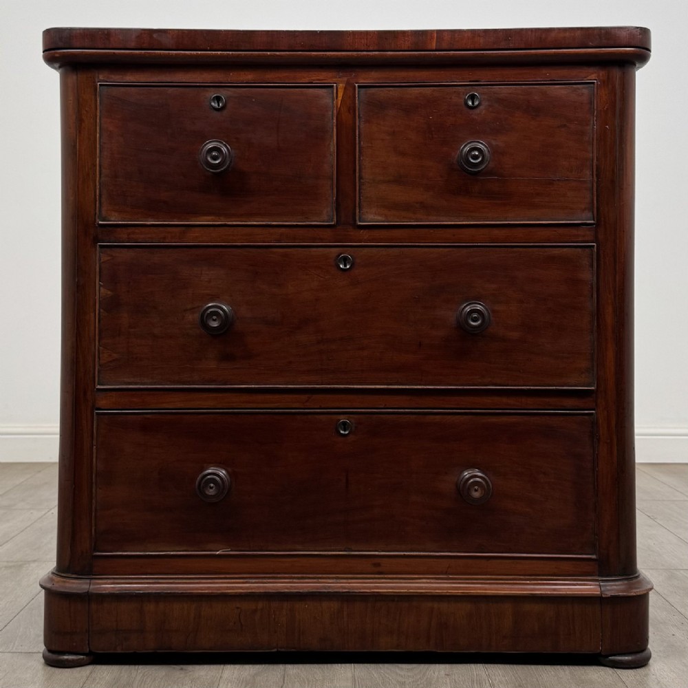 An antique Victorian mahogany chest of drawers featuring two short drawers over two long drawers with turned wooden handles and a plinth base.