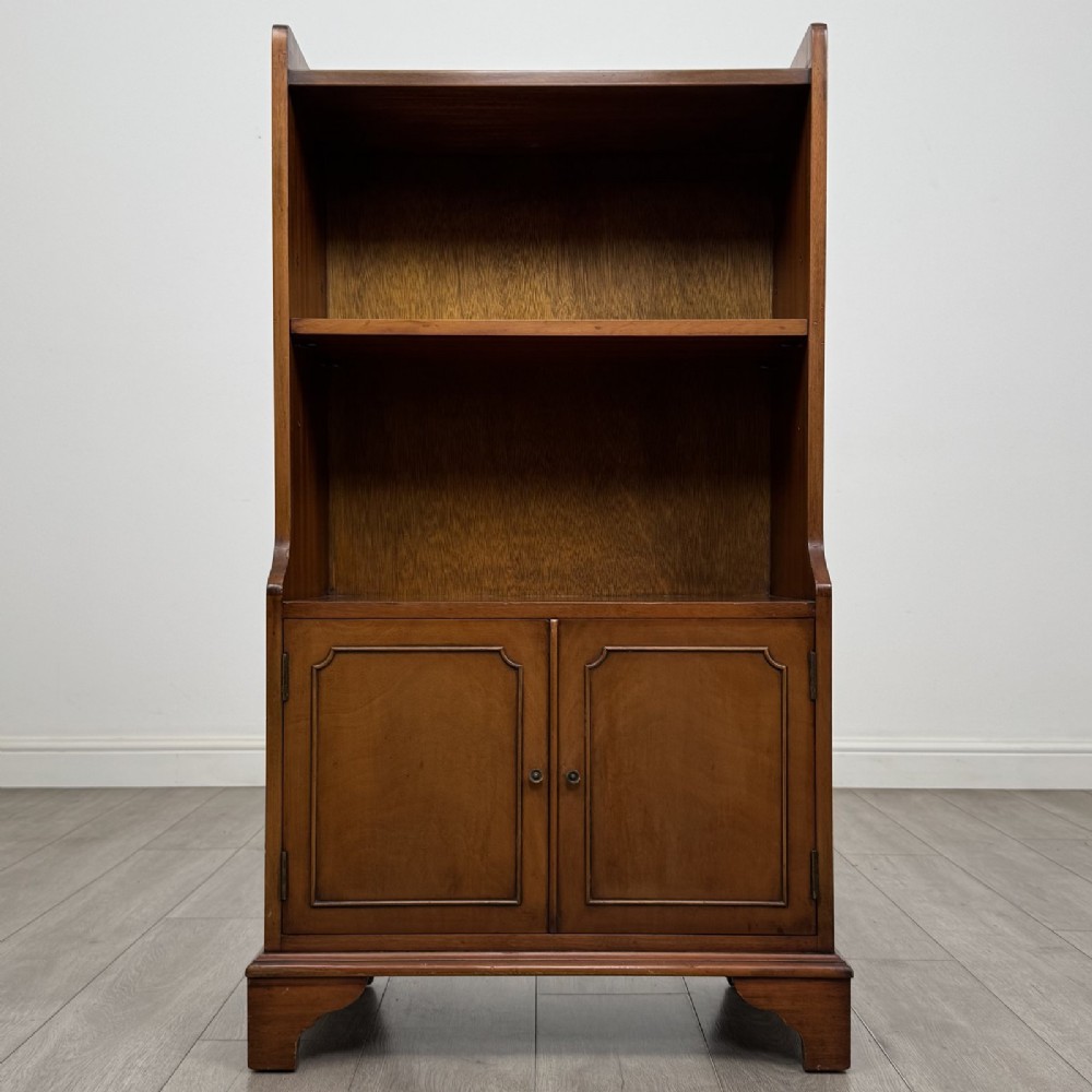 A mahogany open bookcase featuring two upper shelves with shaped side galleries above a two-door lower cupboard on bracket feet.