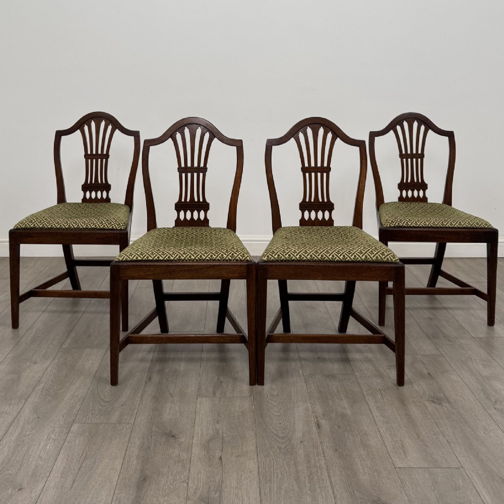 A set of four 18th-century Georgian mahogany dining chairs featuring carved pierced back splats and green patterned upholstered seats.