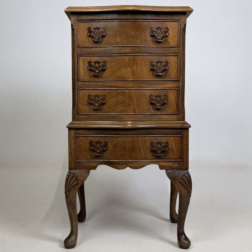 A tall mahogany chest of drawers featuring four stacked drawers with brass handles, resting on carved cabriole legs with pad feet.