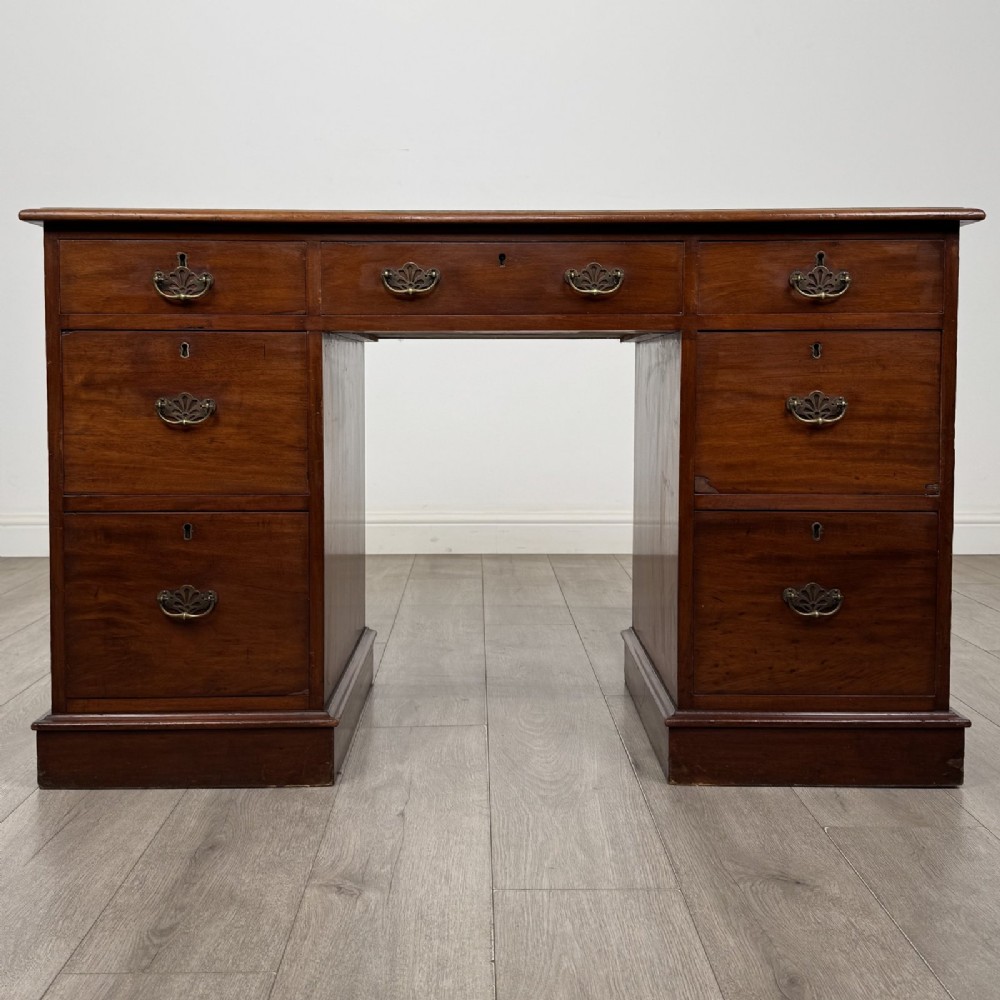 A Victorian mahogany pedestal desk featuring nine drawers fitted with brass swan neck handles and a central kneehole, supported on plinth bases.