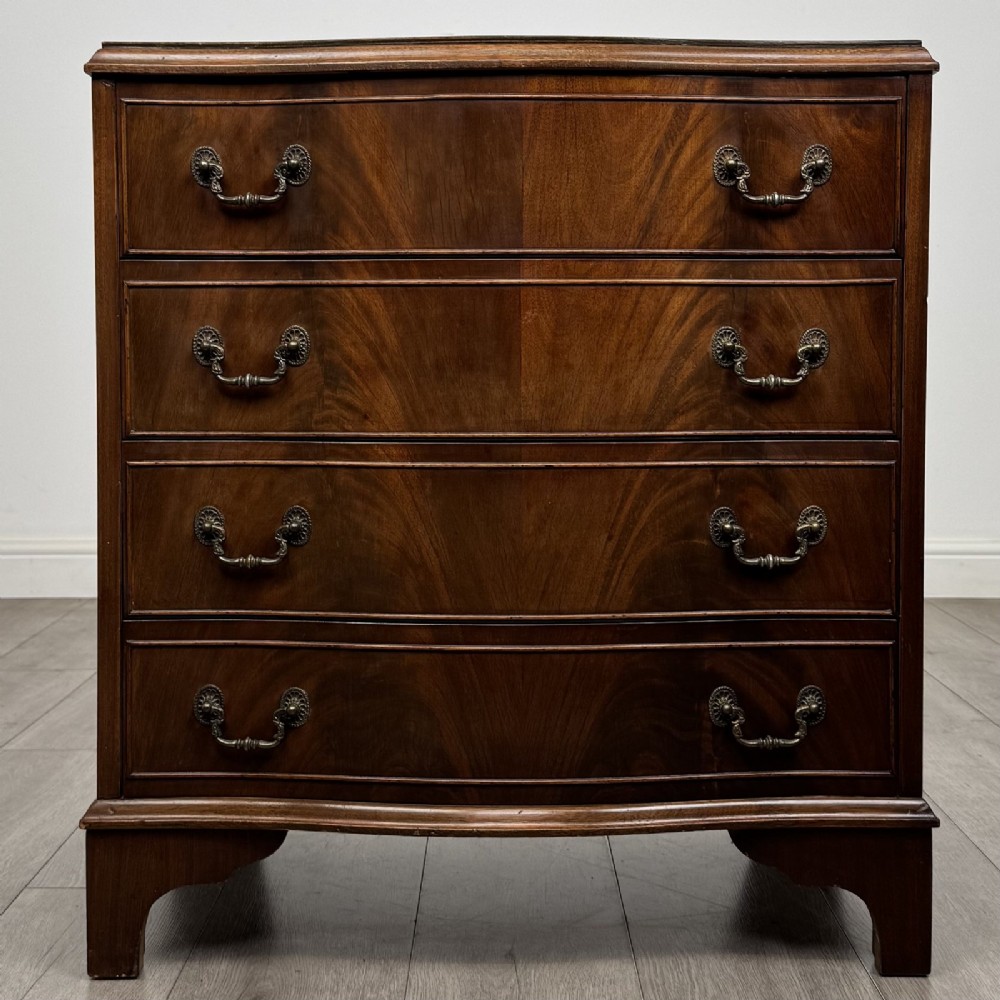 A Georgian style mahogany serpentine chest featuring four graduated drawers with brass drop handles and bracket feet.