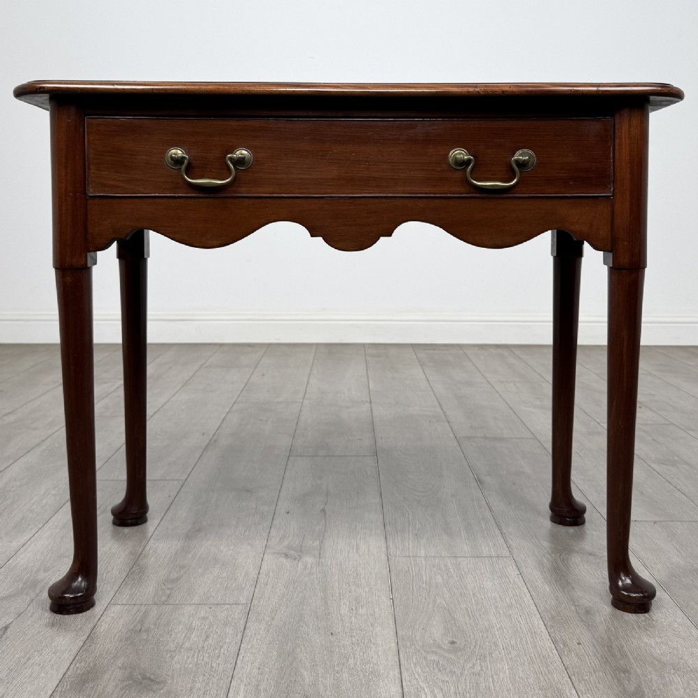 An 18th-century Georgian mahogany side table featuring a single drawer with two brass swan-neck handles, a shaped frieze, and cabriole legs terminating in pad feet.