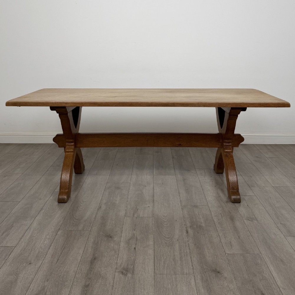 A large 20th-century oak dining table featuring a rectangular wooden top supported by two trestle-style X-frame legs joined by a central horizontal stretcher.