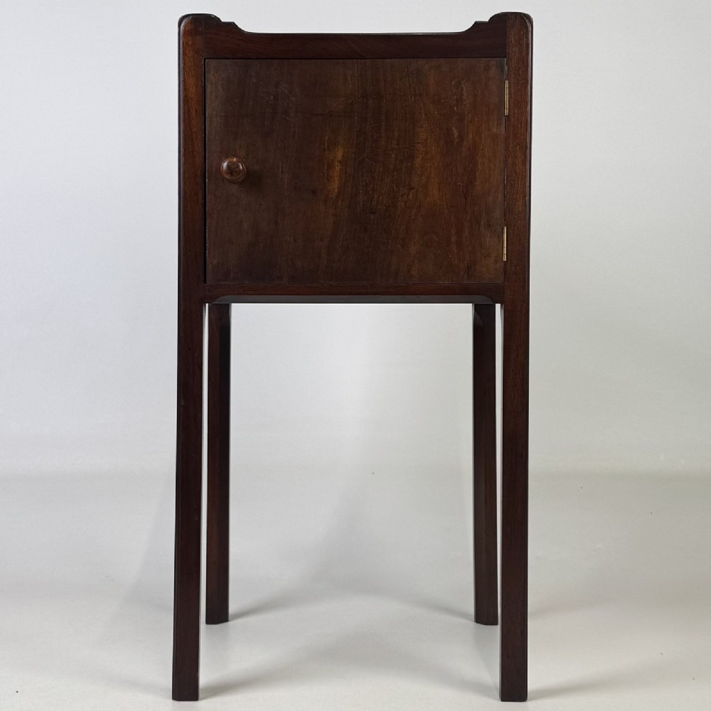 A tall dark mahogany bedside cabinet featuring a gallery tray top, single cupboard door, and square legs.