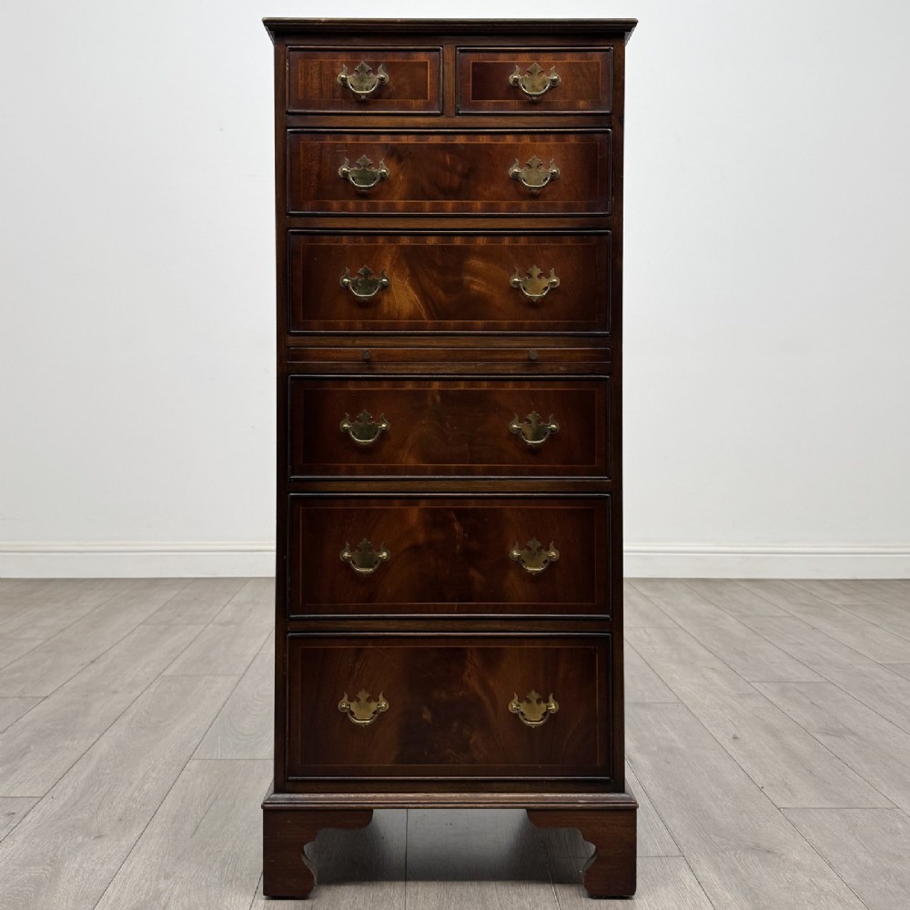 A tall Georgian style mahogany chest of drawers featuring brass swan neck handles, a pull-out brushing slide, and bracket feet.