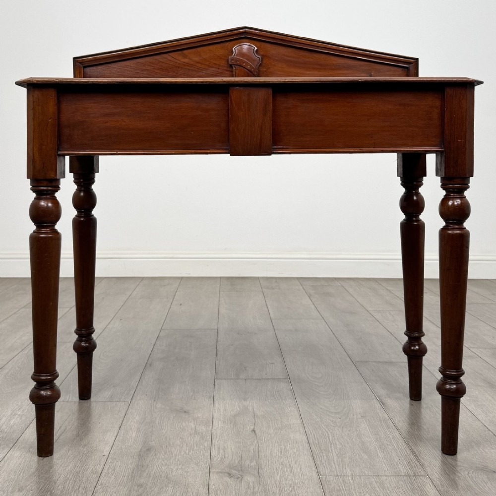 A dark mahogany Victorian side table with turned legs and a low pediment gallery back.