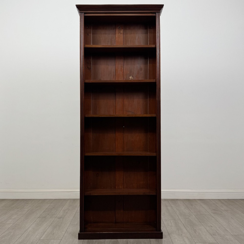 A tall, narrow mahogany open bookcase featuring six shelving compartments, a moulded top cornice, and a solid plinth base.