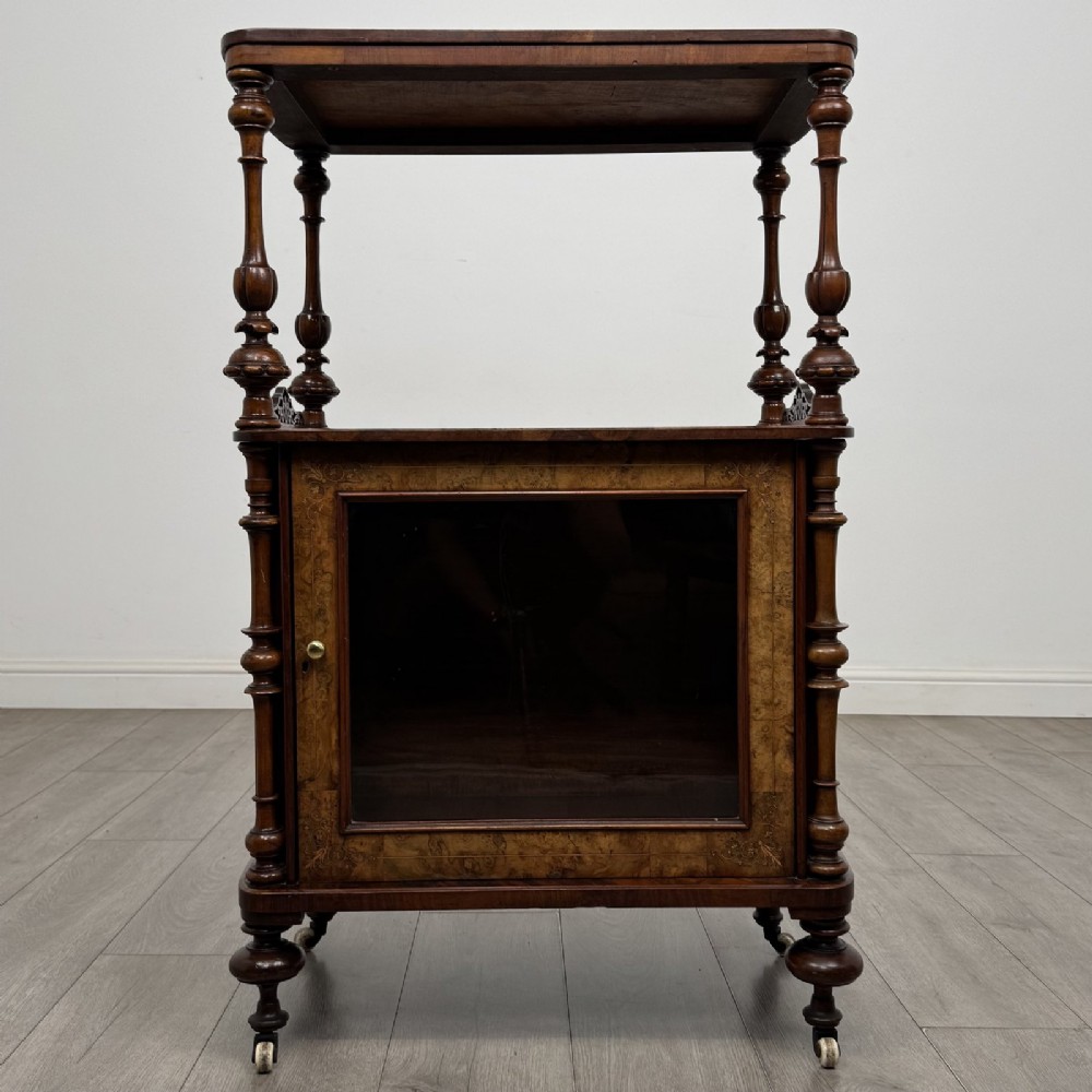A Victorian burr walnut cabinet featuring an upper tier with turned columns above a single glazed cupboard door with marquetry inlay.