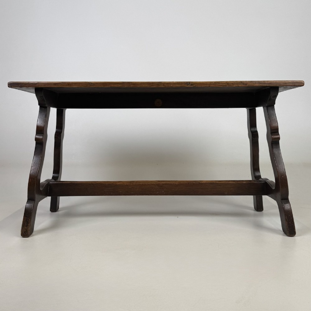 A dark brown oak low coffee table featuring a rectangular plank top supported by shaped trestle end legs joined by a low central stretcher.