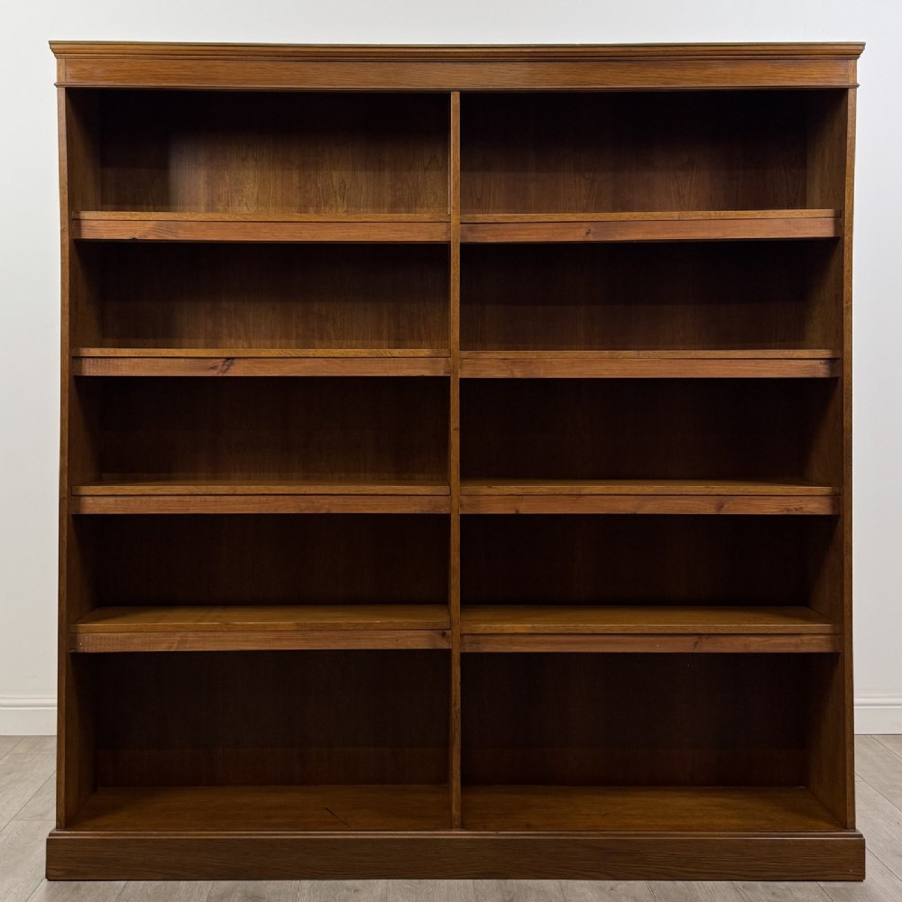 A large 20th-century double-width open oak bookcase with a moulded cornice, central vertical divider, and ten spacious open shelves.