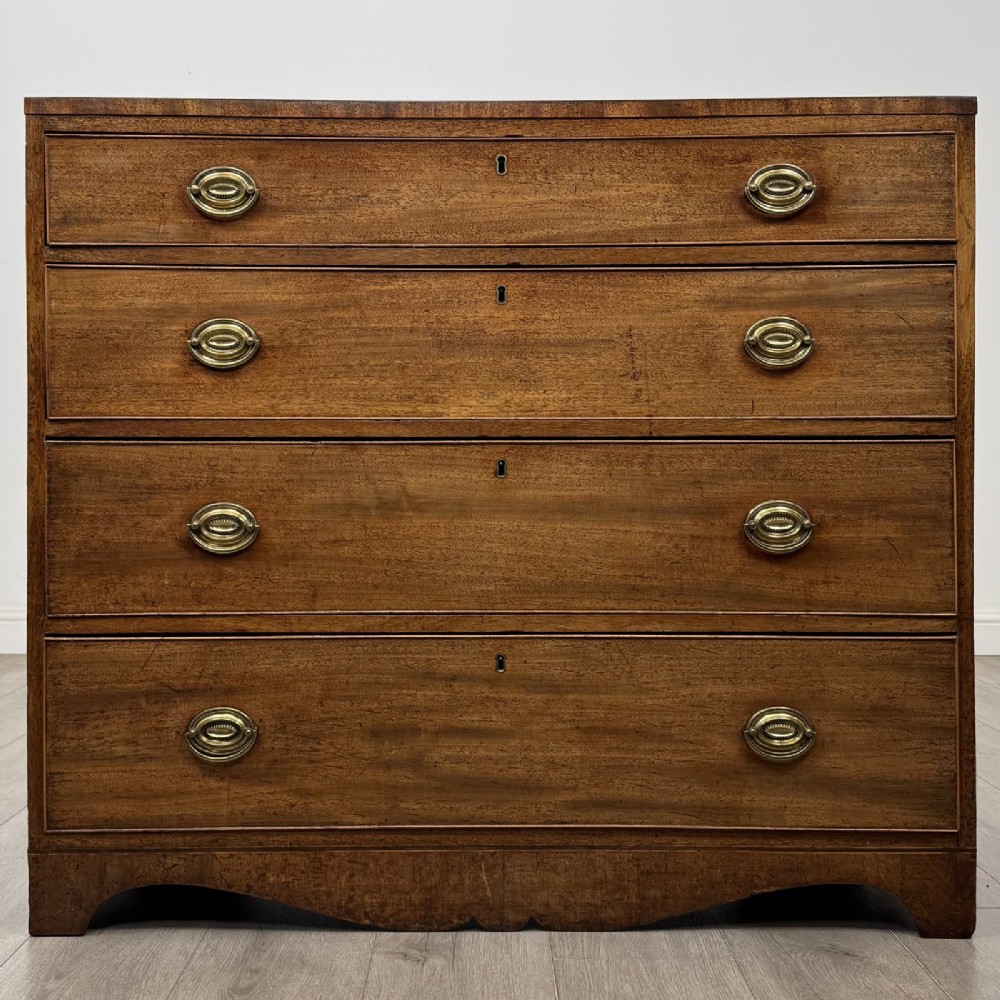 A Georgian mahogany chest of drawers featuring four graduated drawers with oval brass handles and splayed bracket feet.