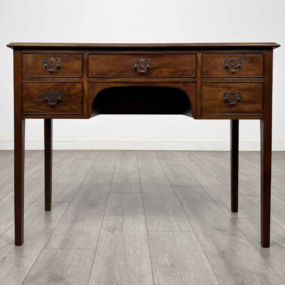 A small Georgian style mahogany writing desk featuring five drawers with brass handles and straight tapered legs.
