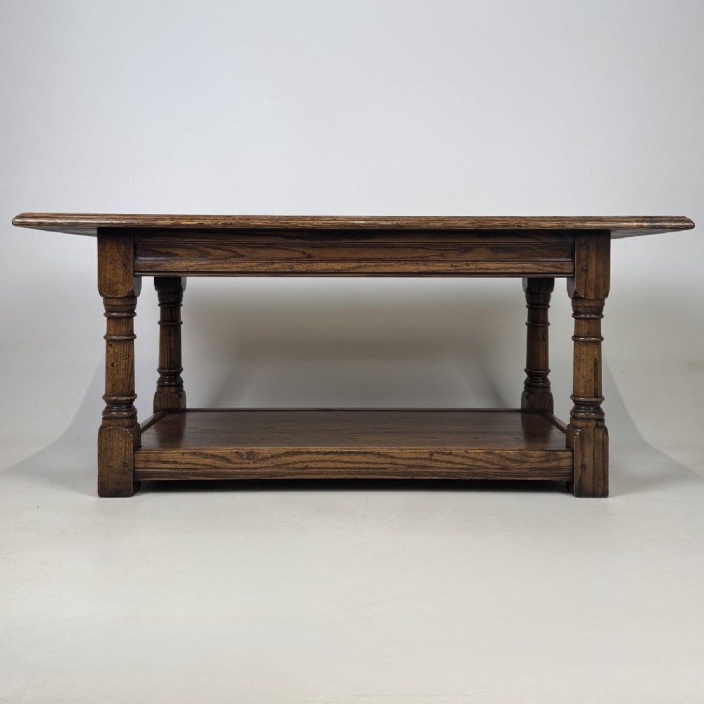 A rectangular dark oak Jacobean style coffee table featuring turned baluster legs and a lower potboard shelf.