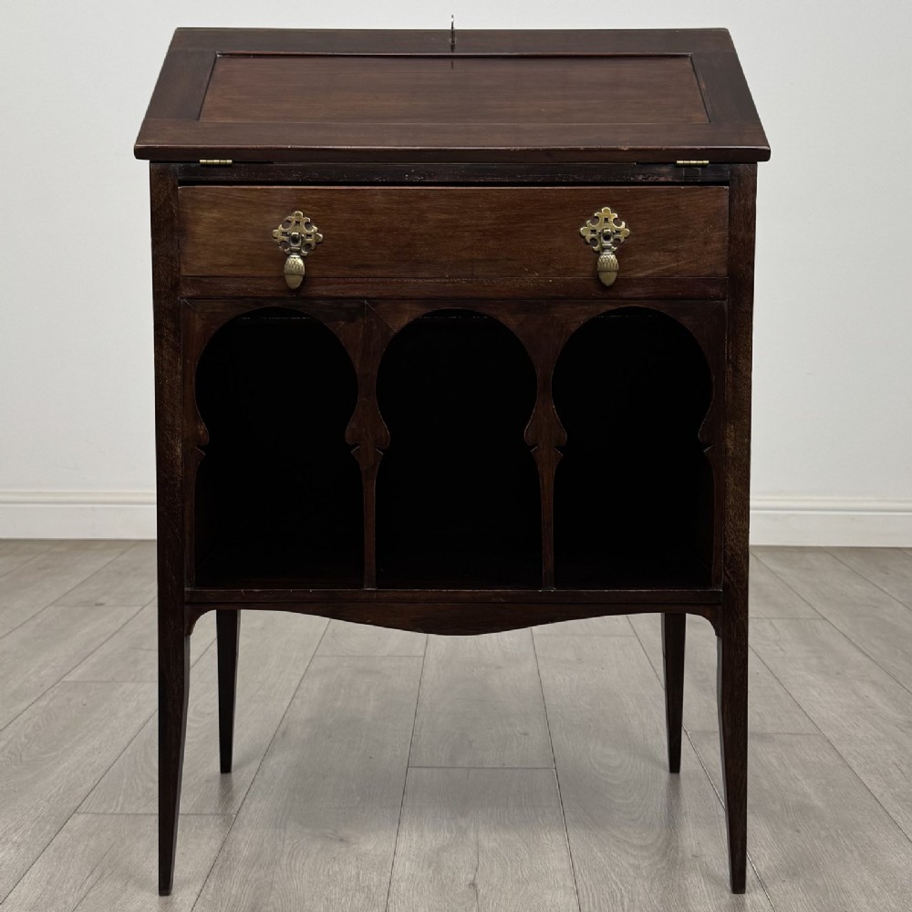An Edwardian dark mahogany bureau featuring a slant-front writing lid, a single drawer with brass drop handles, open lower compartment with arches, and tapered legs.