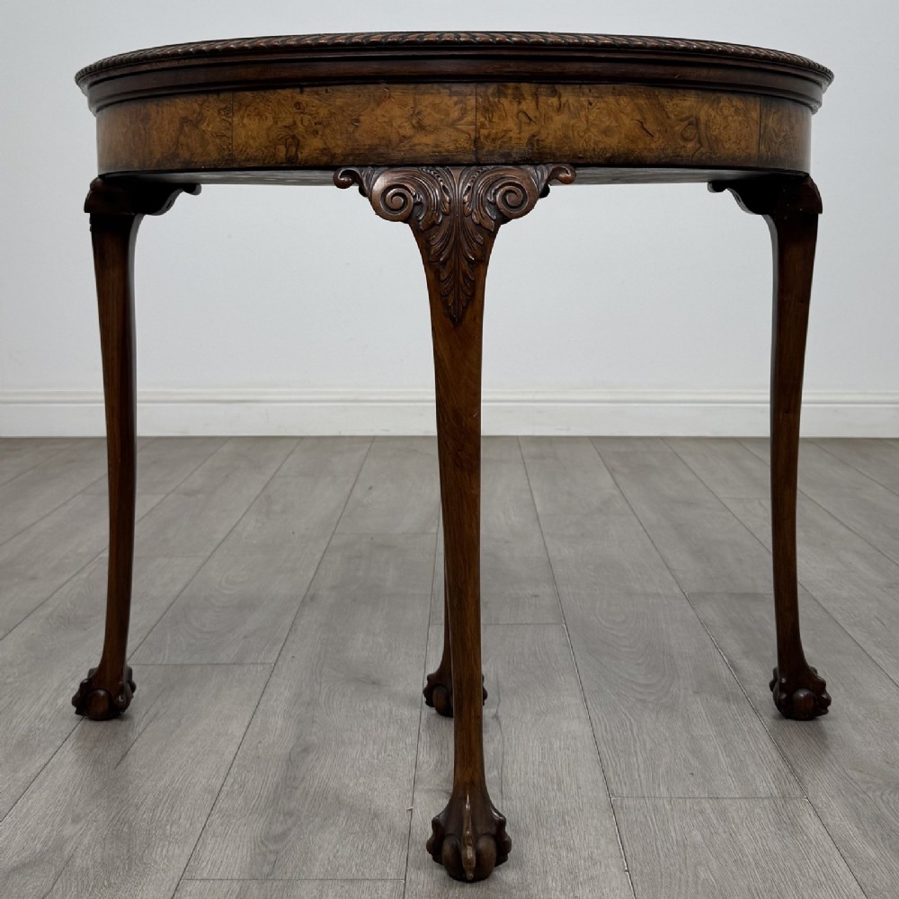 A Georgian style burr walnut card table featuring carved cabriole legs terminating in ball and claw feet.