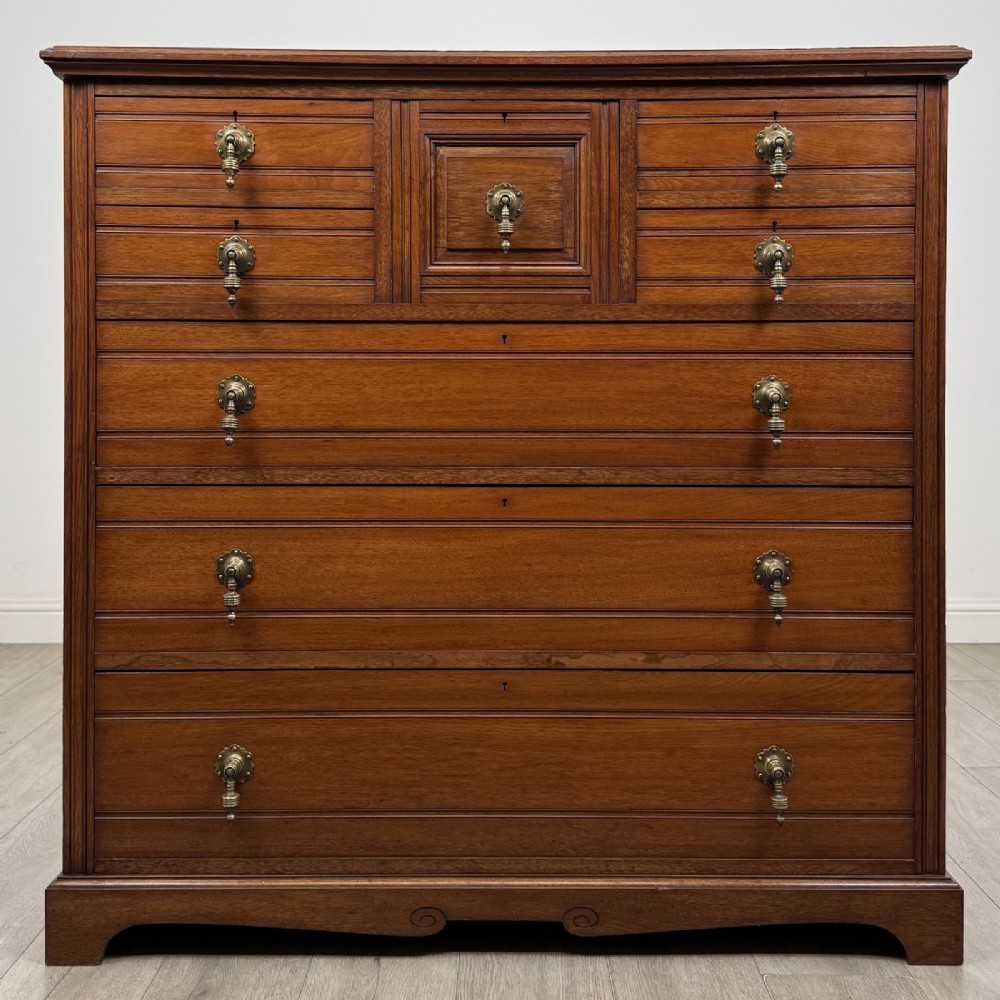 A late Victorian walnut chest of drawers featuring a central square hat drawer flanked by smaller drawers above three long drawers with reeded moulding.