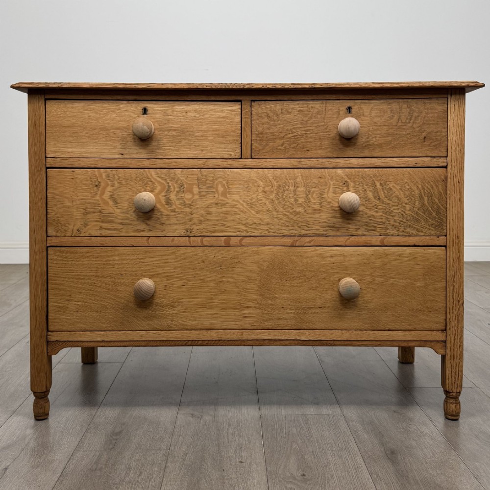 An Edwardian quarter-sawn oak chest of drawers with two short drawers over two long drawers and turned wooden handles.