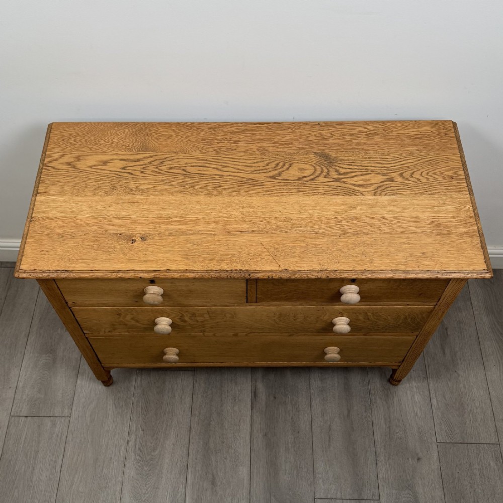 An Edwardian quarter-sawn oak chest of drawers with two short drawers over two long drawers and turned wooden handles. View IX
