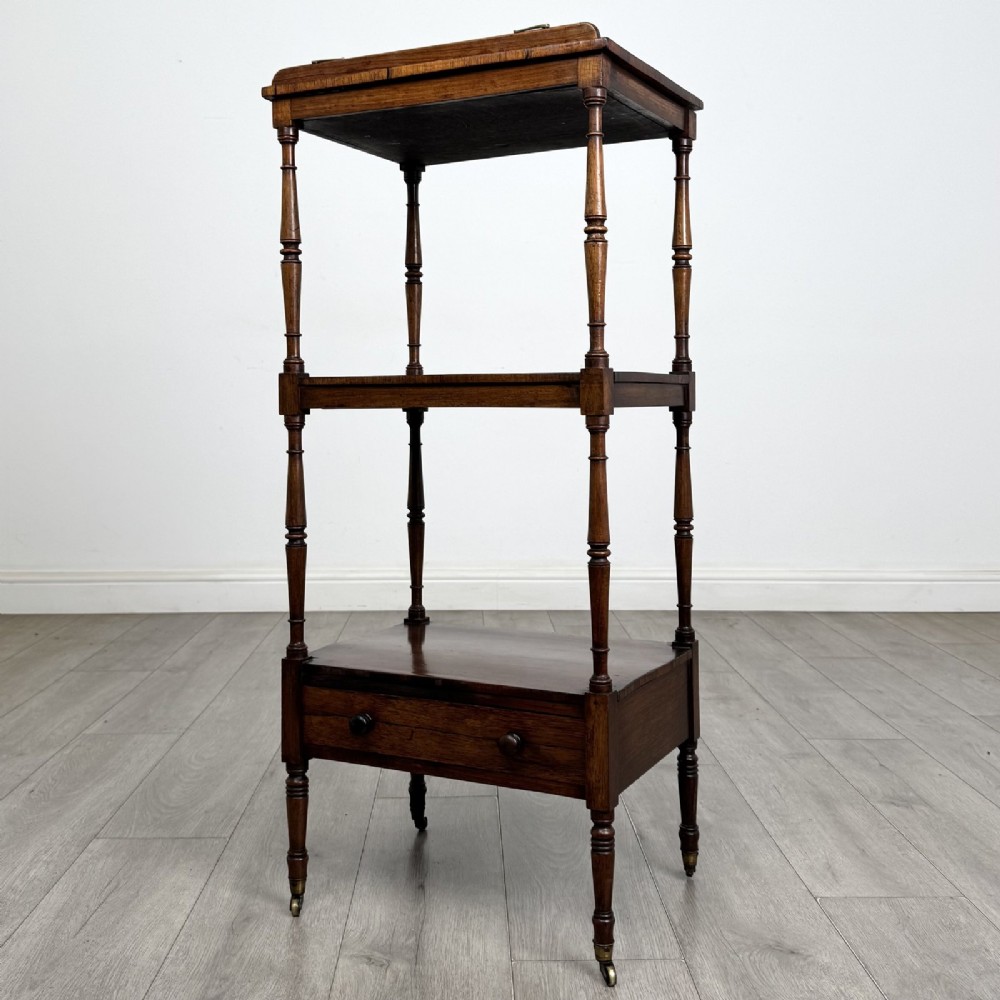 An antique Regency rosewood three-tiered whatnot featuring an adjustable angled reading slope top, slender turned upright supports, a bottom drawer, and brass castors. View III