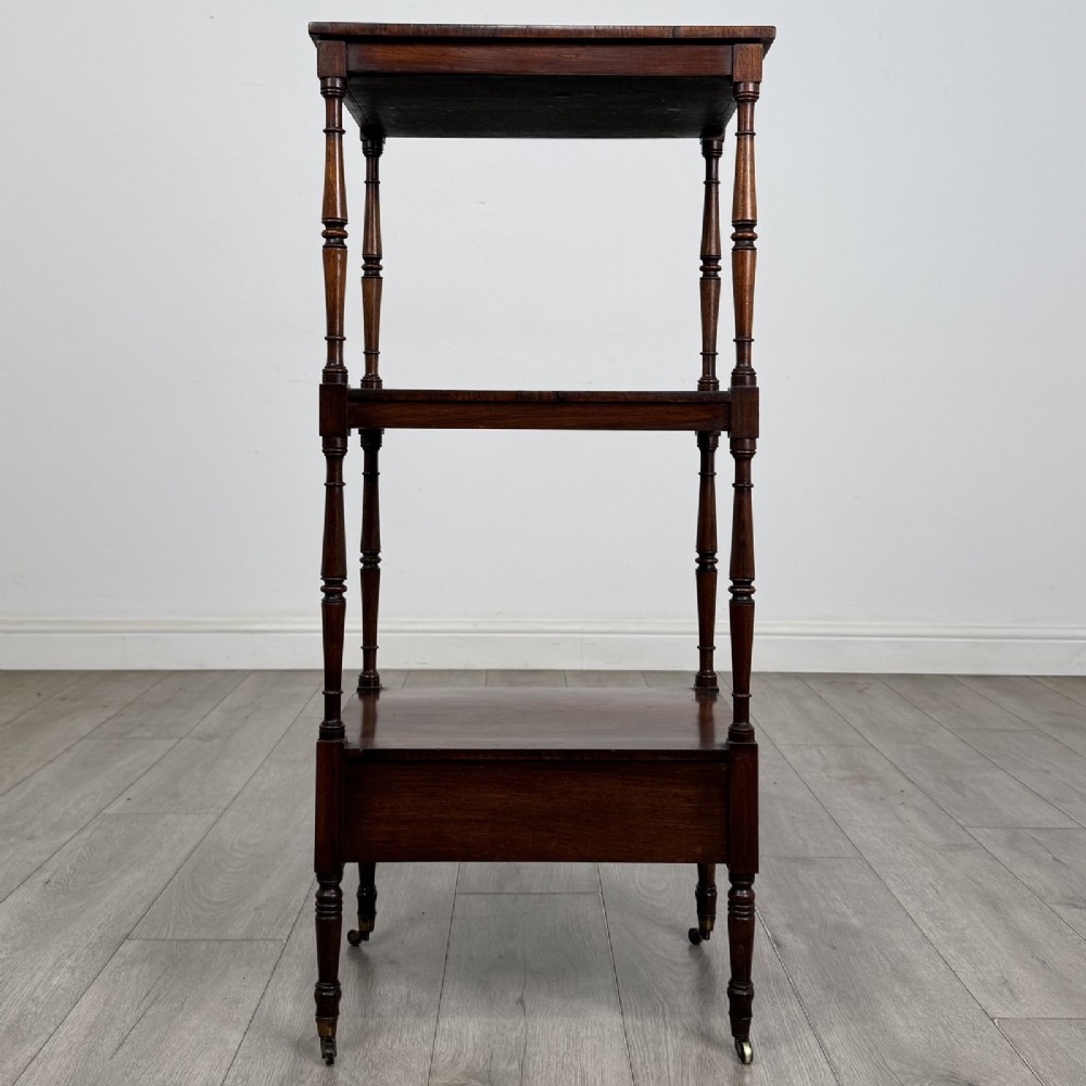 An antique Regency rosewood three-tiered whatnot featuring an adjustable angled reading slope top, slender turned upright supports, a bottom drawer, and brass castors. View VII
