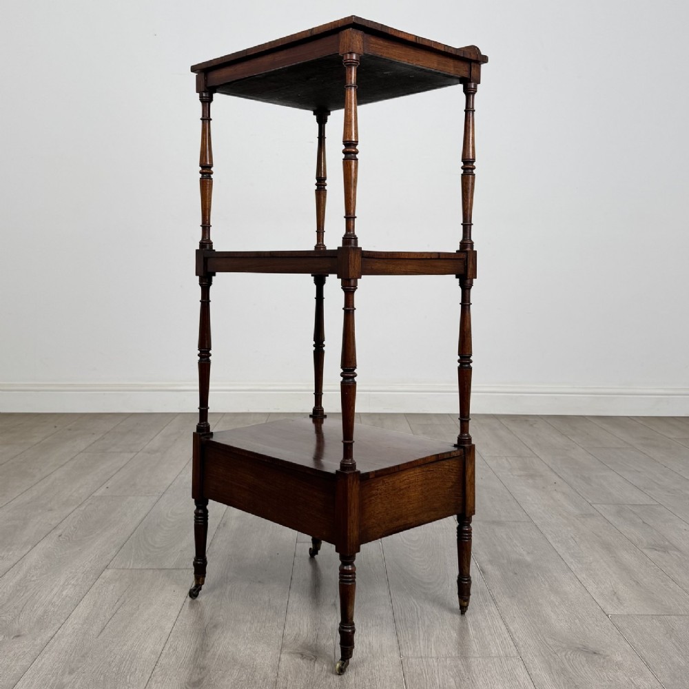An antique Regency rosewood three-tiered whatnot featuring an adjustable angled reading slope top, slender turned upright supports, a bottom drawer, and brass castors. View VIII