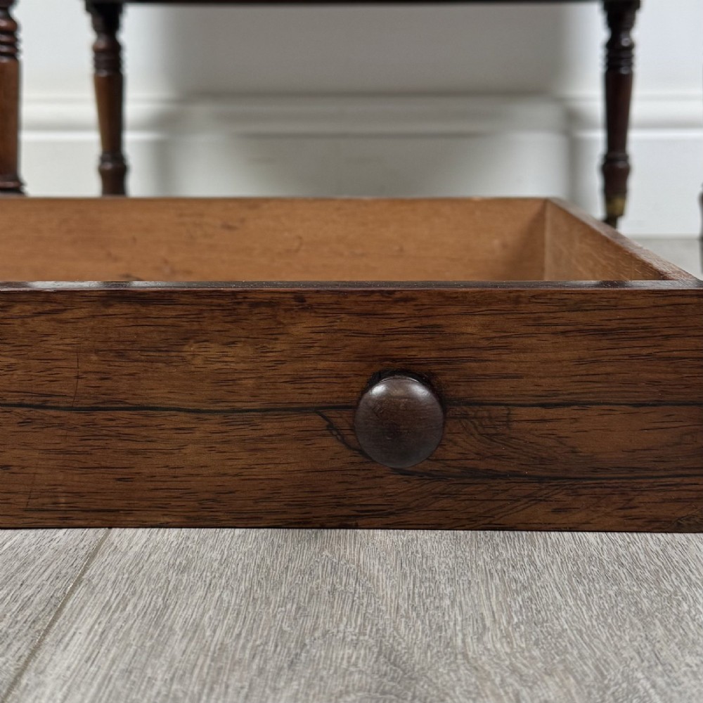 An antique Regency rosewood three-tiered whatnot featuring an adjustable angled reading slope top, slender turned upright supports, a bottom drawer, and brass castors. View XIII