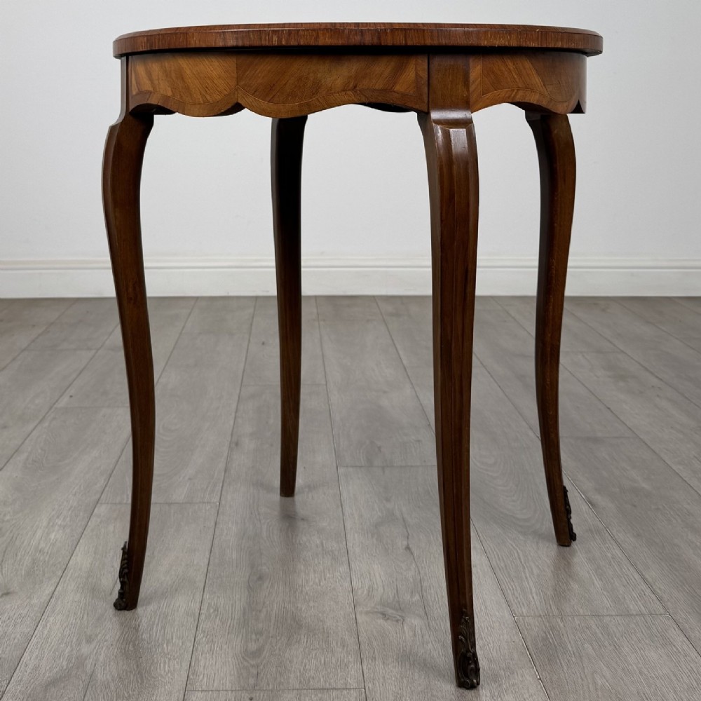 A circular French Louis XV style lamp table featuring slender cabriole legs, marquetry wood grain pattern, an undulating apron, and metal sabot feet. View II