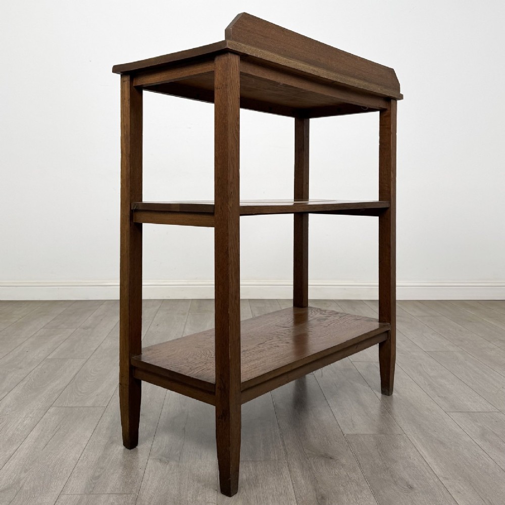 An antique Edwardian dark oak buffet featuring three open rectangular shelves supported by straight tapered legs. View IV