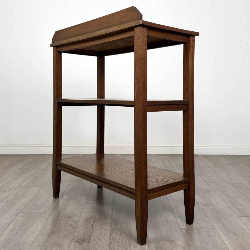 An antique Edwardian dark oak buffet featuring three open rectangular shelves supported by straight tapered legs. View VI