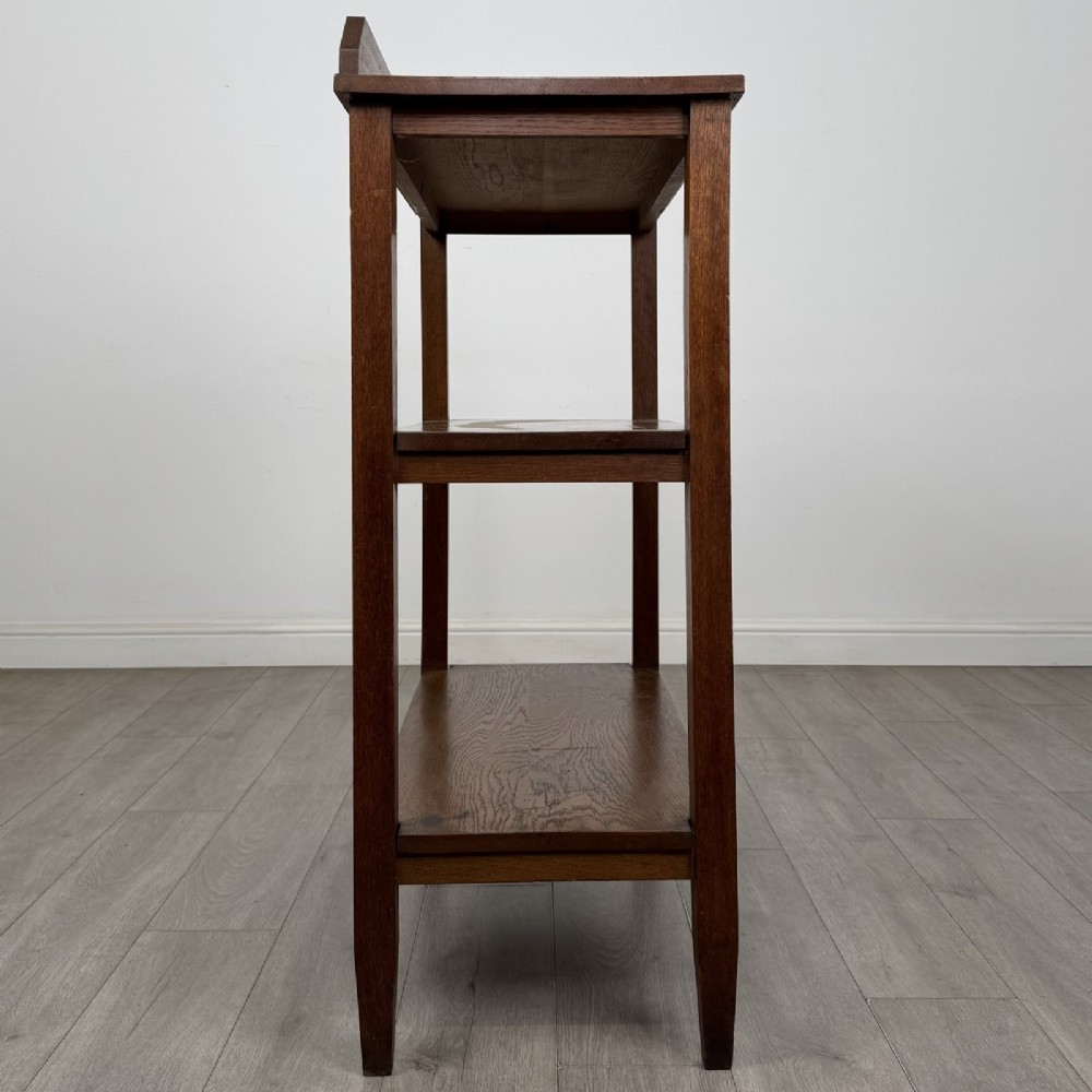 An antique Edwardian dark oak buffet featuring three open rectangular shelves supported by straight tapered legs. View VII