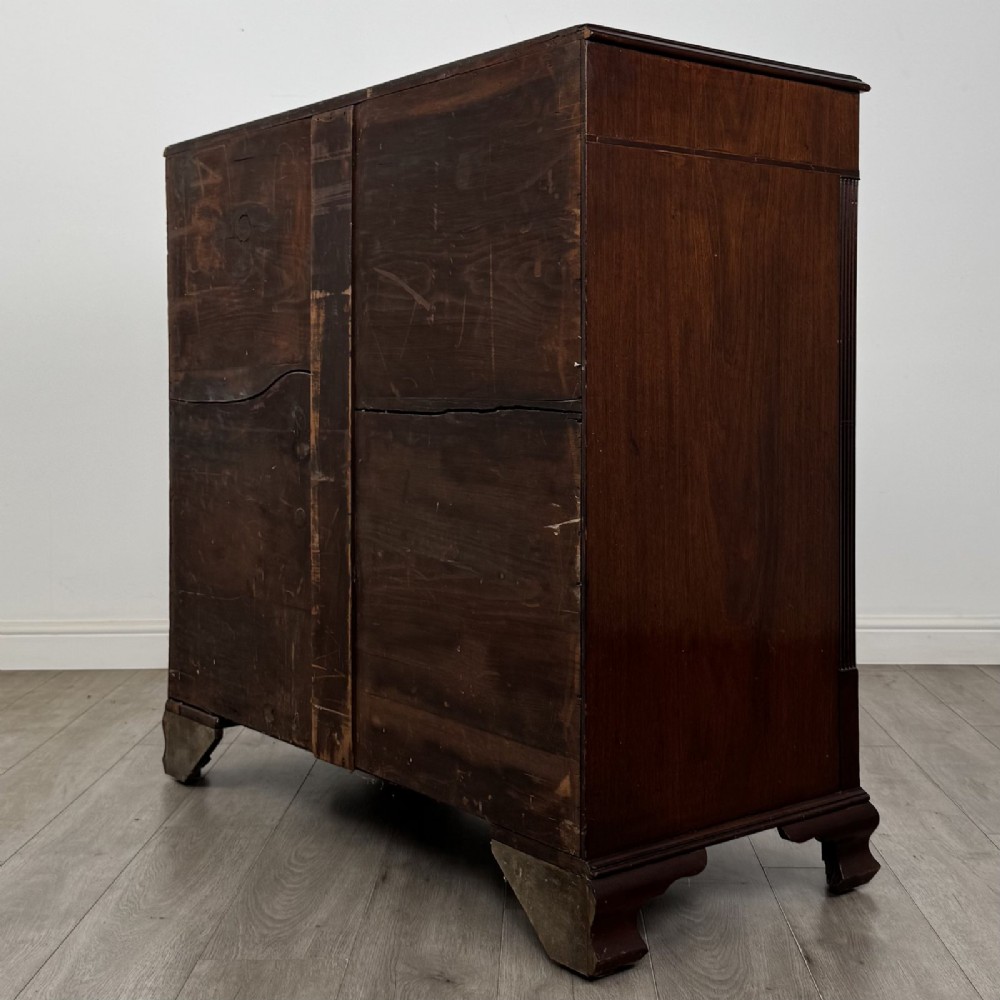 An 18th-century Georgian mahogany chest of drawers featuring inlaid stringing along the top frieze, two short drawers above three long drawers, brass swan-neck handles, fluted pilasters, and bracket feet. View VI
