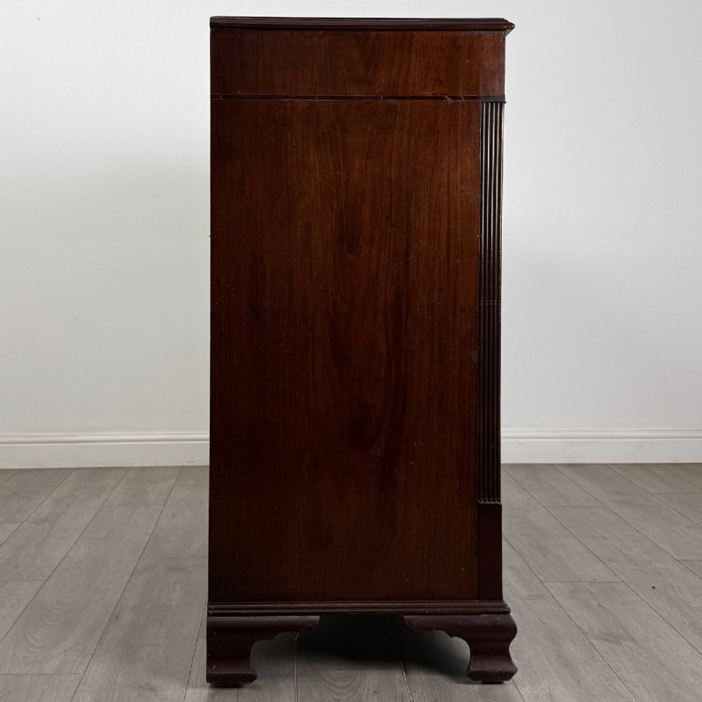 An 18th-century Georgian mahogany chest of drawers featuring inlaid stringing along the top frieze, two short drawers above three long drawers, brass swan-neck handles, fluted pilasters, and bracket feet. View VII