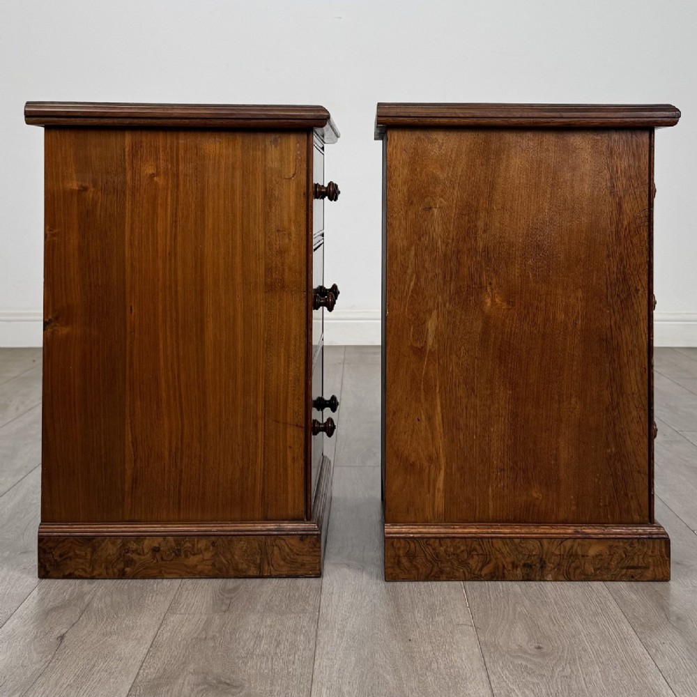 A pair of Victorian burr walnut bedside cabinets featuring three drawers each with turned wooden knobs and a plinth base. View VIII