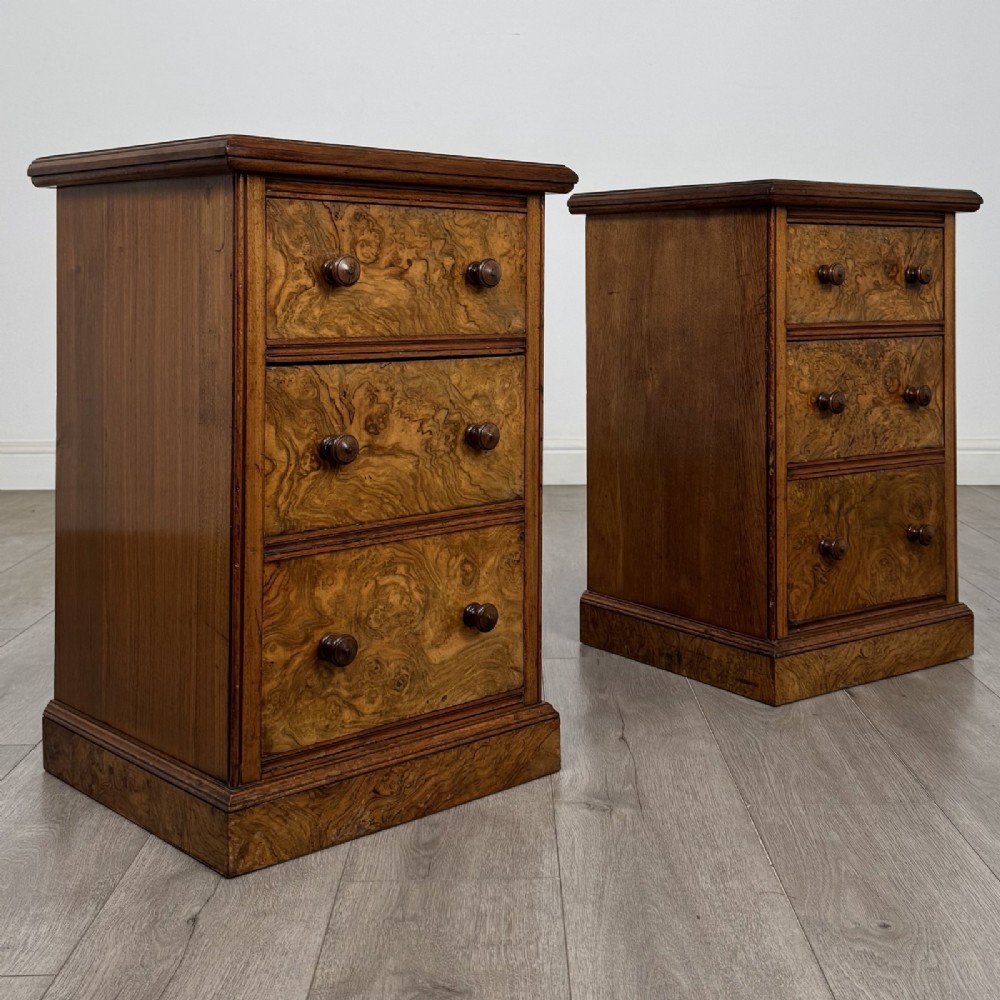 A pair of Victorian burr walnut bedside cabinets featuring three drawers each with turned wooden knobs and a plinth base. View IX