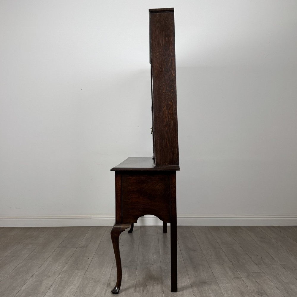 A dark oak Queen Anne style dresser featuring an open-shelf upper rack with side cupboards above two drawers supported by cabriole legs. View III