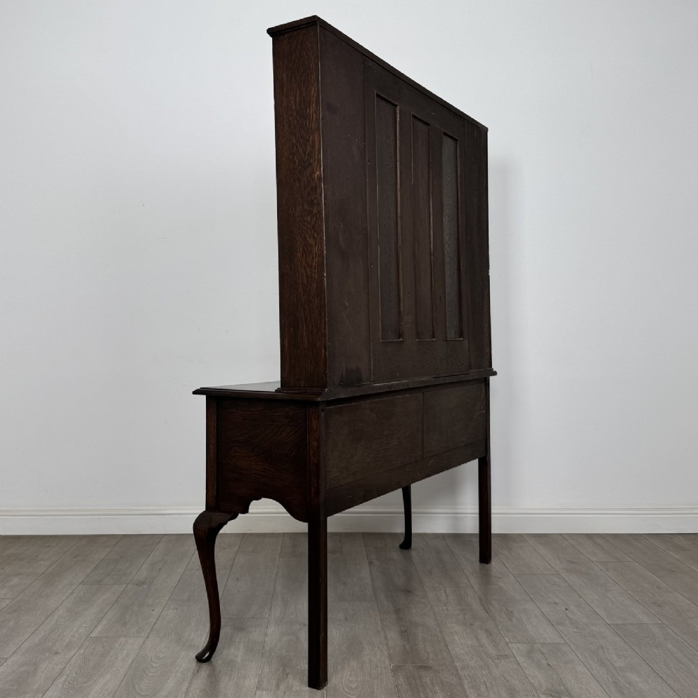A dark oak Queen Anne style dresser featuring an open-shelf upper rack with side cupboards above two drawers supported by cabriole legs. View IV