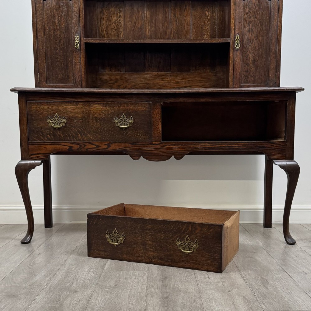 A dark oak Queen Anne style dresser featuring an open-shelf upper rack with side cupboards above two drawers supported by cabriole legs. View XI