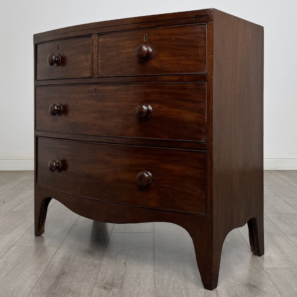 A 19th-century dark mahogany bow front chest of drawers featuring two short drawers above two long drawers with turned wooden handles and bracket feet. View II