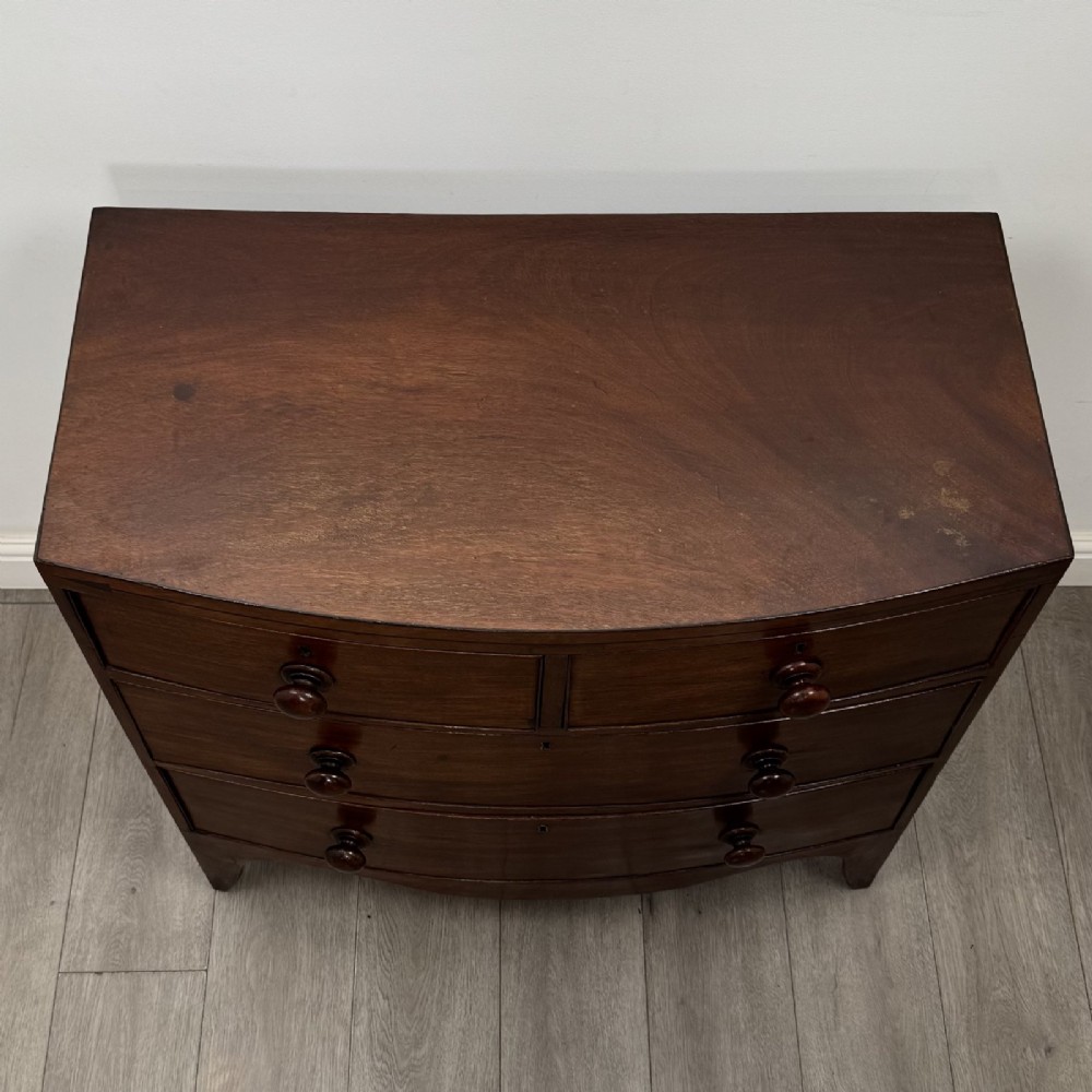 A 19th-century dark mahogany bow front chest of drawers featuring two short drawers above two long drawers with turned wooden handles and bracket feet. View IX