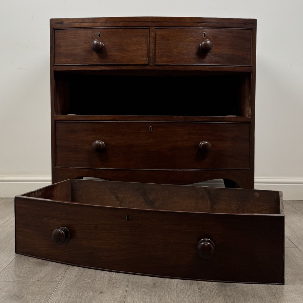 A 19th-century dark mahogany bow front chest of drawers featuring two short drawers above two long drawers with turned wooden handles and bracket feet. View X