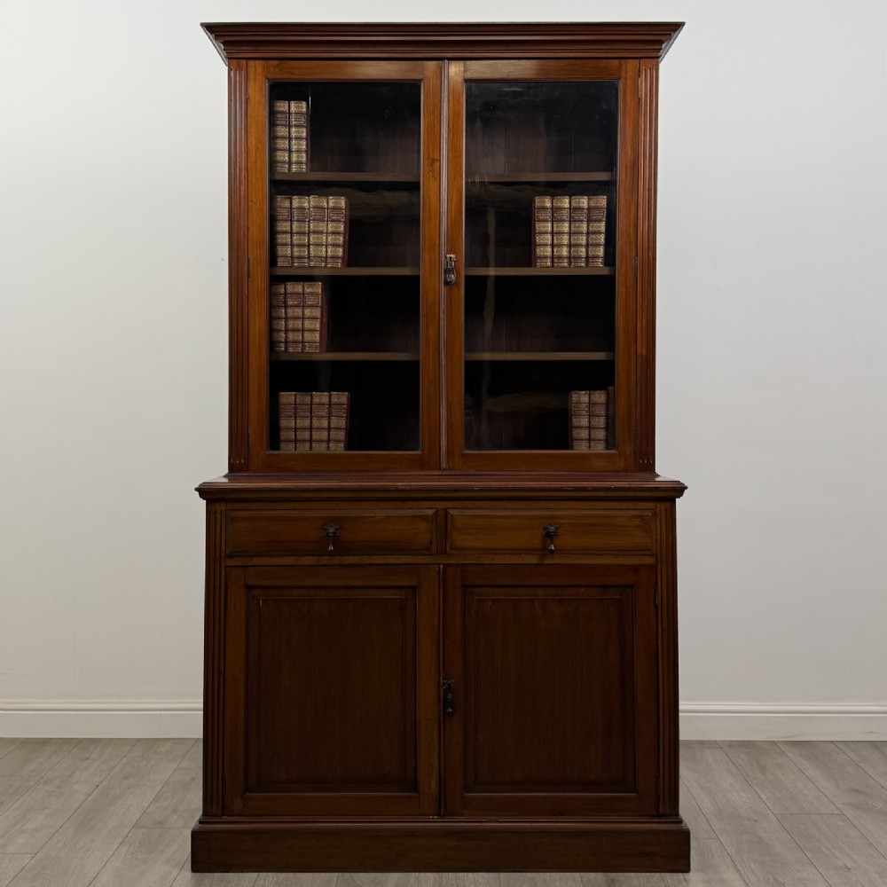 An antique Victorian mahogany glazed bookcase featuring two upper glass doors, twin frieze drawers, and lower panelled doors. View II