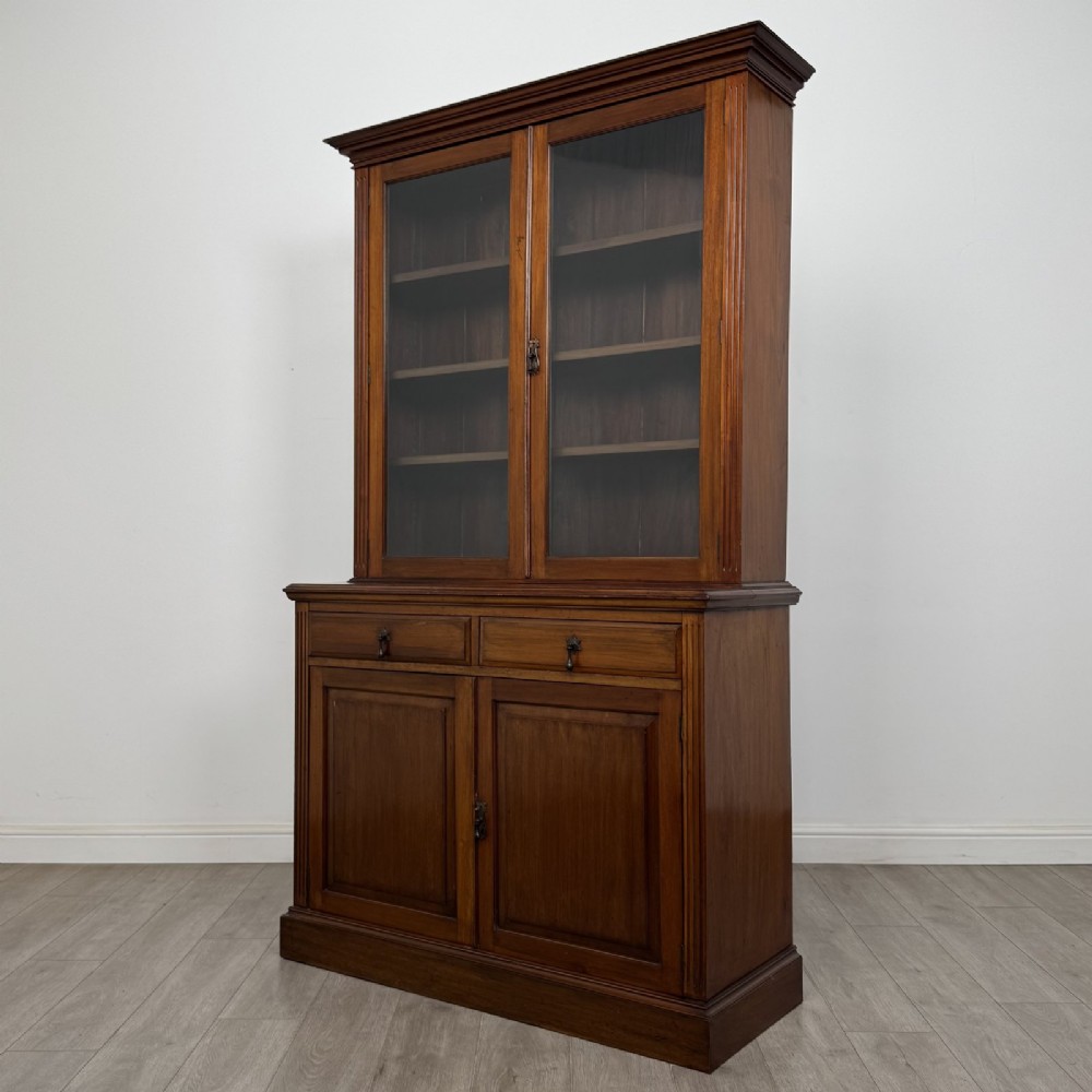 An antique Victorian mahogany glazed bookcase featuring two upper glass doors, twin frieze drawers, and lower panelled doors. View III