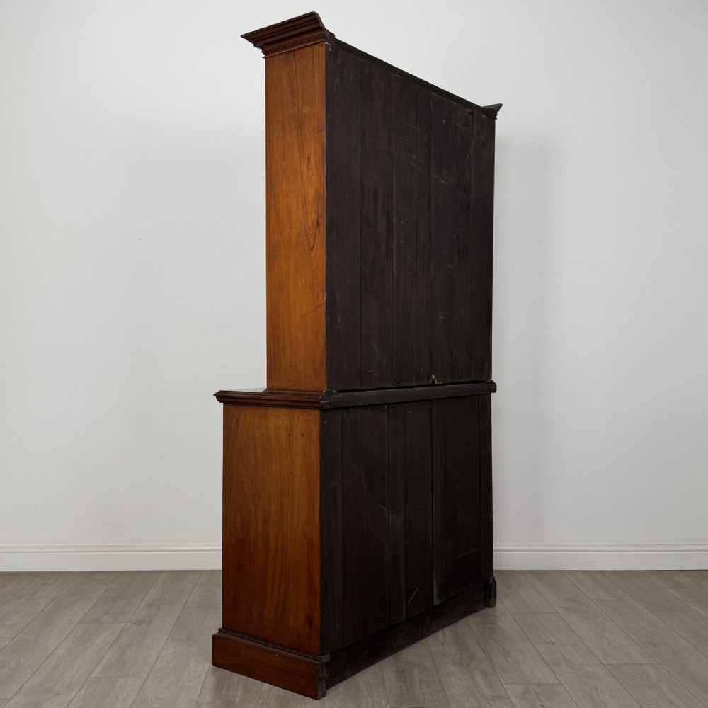 An antique Victorian mahogany glazed bookcase featuring two upper glass doors, twin frieze drawers, and lower panelled doors. View V