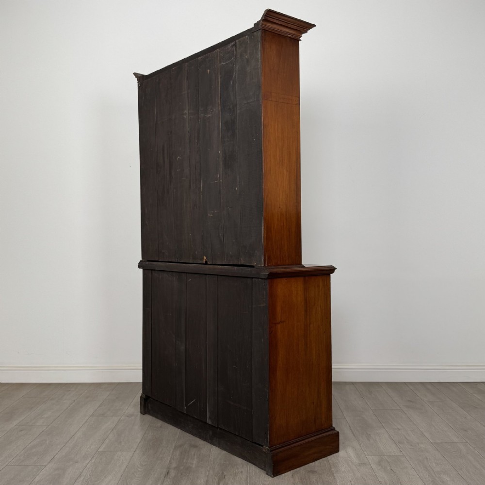 An antique Victorian mahogany glazed bookcase featuring two upper glass doors, twin frieze drawers, and lower panelled doors. View VII