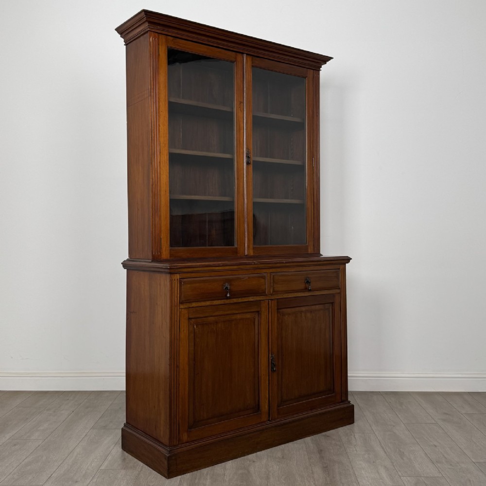 An antique Victorian mahogany glazed bookcase featuring two upper glass doors, twin frieze drawers, and lower panelled doors. View IX